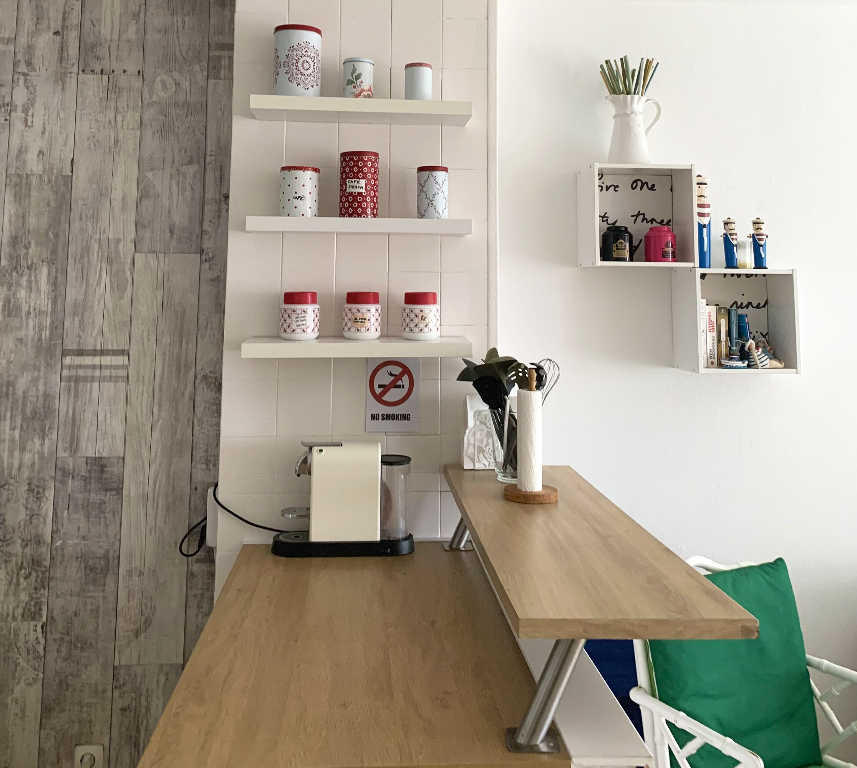 Ein Küchenbereich mit einer Kaffeemaschine, einem Rauchverbotsschild und Regalen mit Gläsern.
