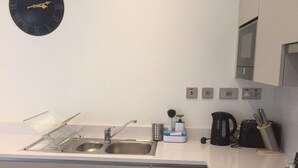 A modern kitchen with a sink, a kettle, and a clock on the wall. - Modern Apartment By Creatick (Reading)