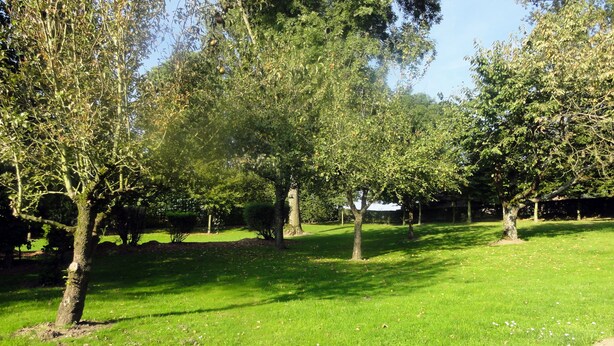 A well-maintained grassy area with trees and a brick pathway. - Gite in France, 3 stars, 11 prs, comfortable, relaxing, in natural environment (Vacqueriette-Erquières)