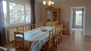 A dining room with a long table, wooden chairs, a cabinet with glass doors, and a chandelier. - Gite in France, 3 stars, 11 prs, comfortable, relaxing, in natural environment (Vacqueriette-Erquières)
