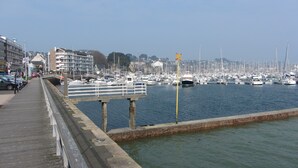 A marina with boats docked, a pedestrian walkway, and buildings in the background. - Gîtes Les COSTANS & A Proximité plages 800M & Commerces 300M (Perros-Guirec)