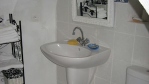Ein Badezimmer mit einem weißen Waschbecken, einer blauen Toilette und einem Handtuchhalter mit gefalteten Handtüchern.