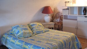 Ein Schlafzimmer mit einem Bett, einem Nachttisch, einer Lampe, einem Ventilator und einem Schrank.