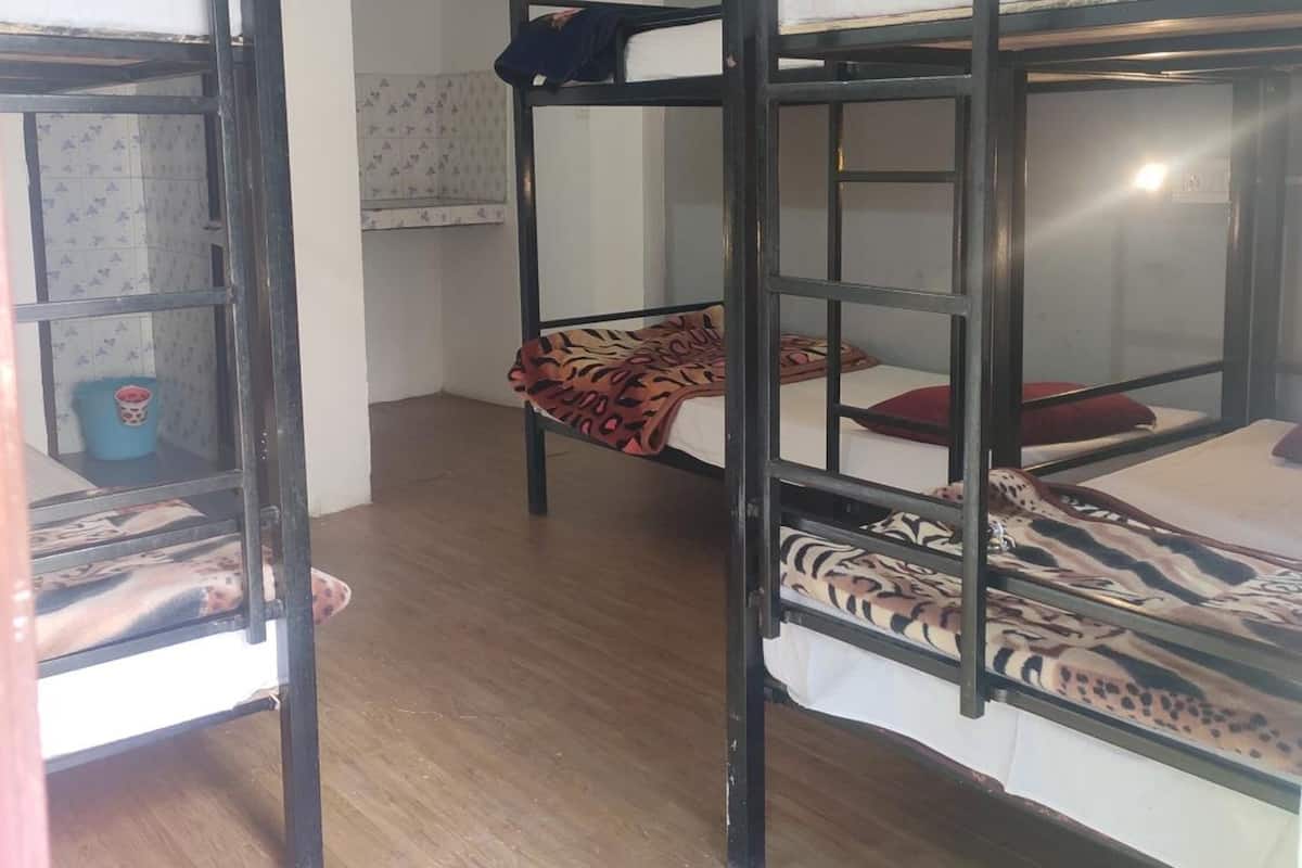 Ein Schlafsaalzimmer mit Etagenbetten, Holzboden und einer kleinen Küchenzeile.