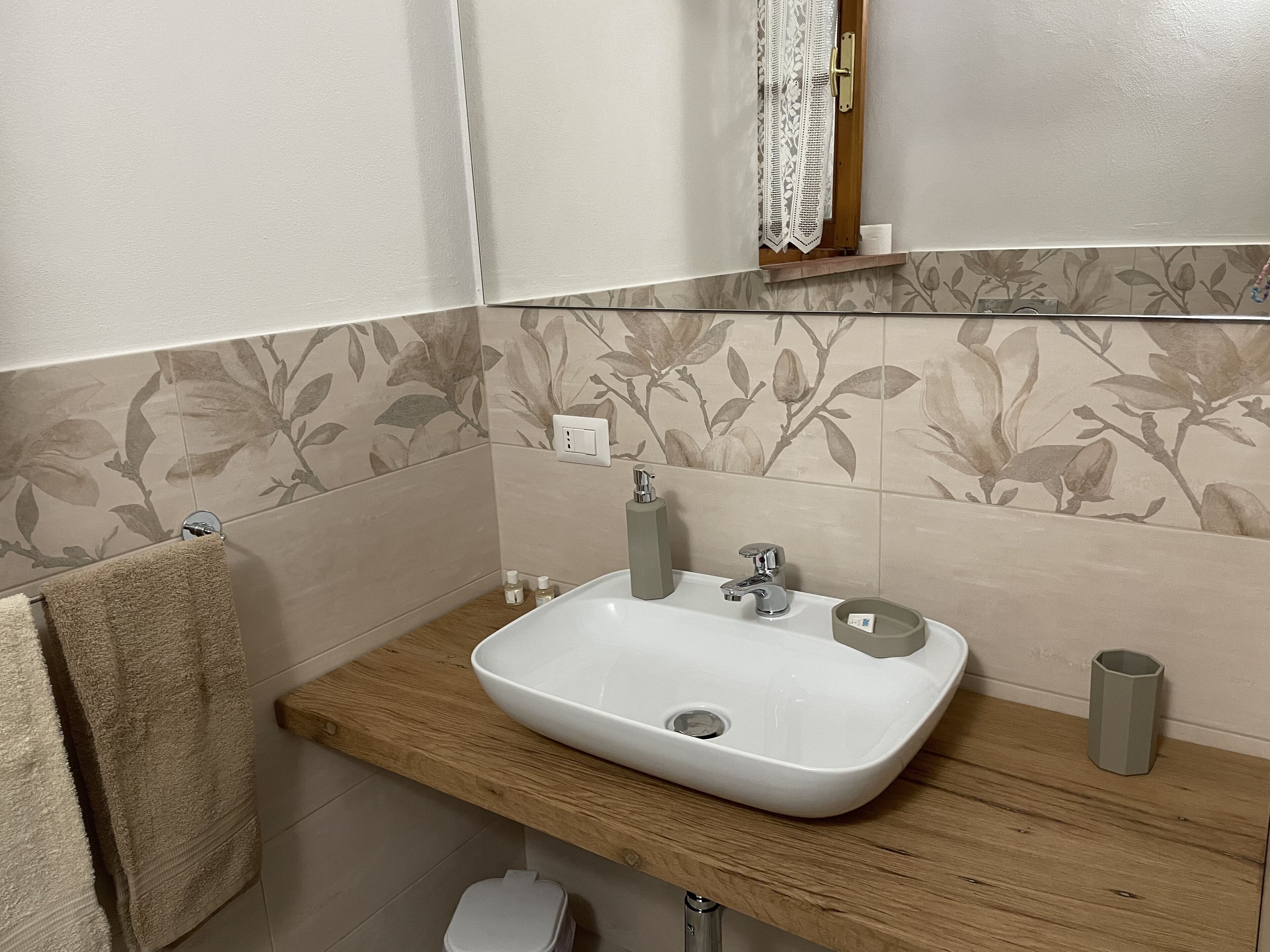 A bathroom with a white sink, wooden countertop, and a towel rack.