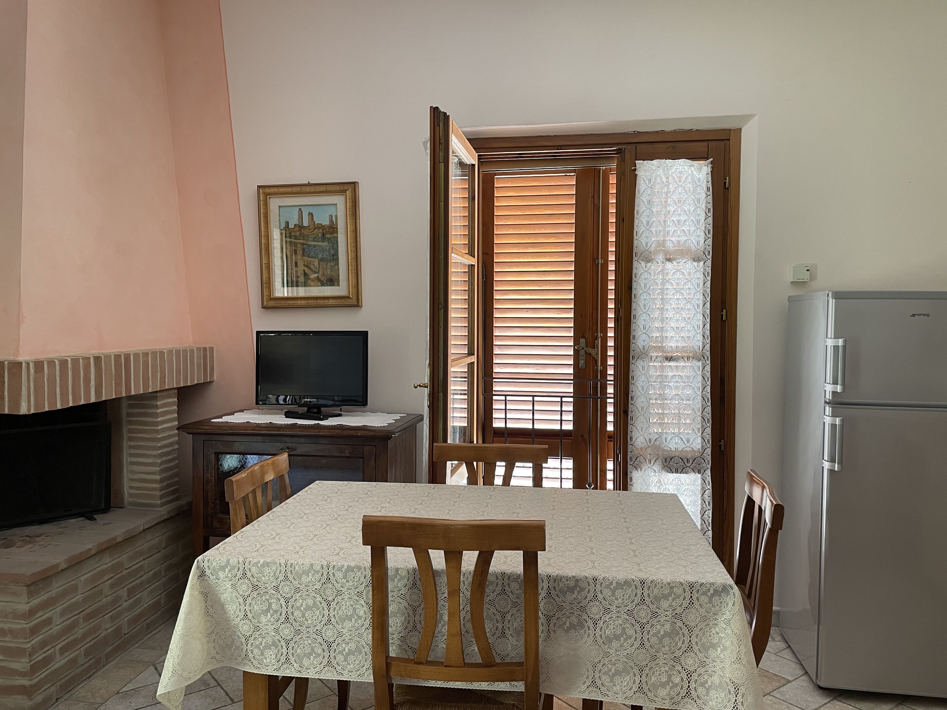 A dining area with a table, chairs, a television, and a refrigerator.