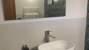 A bathroom with a white sink, a mirror, and a towel rack.