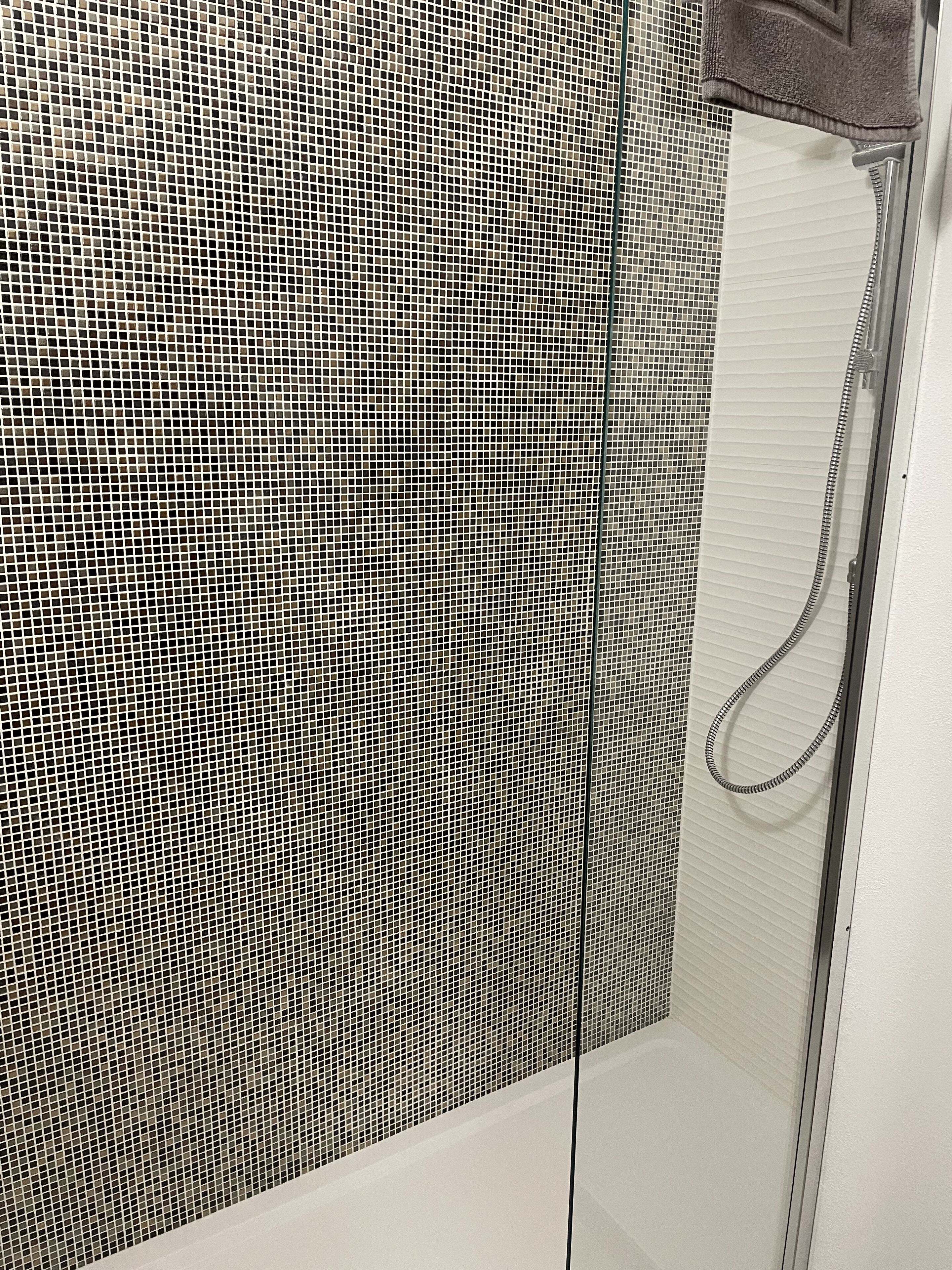 Uma casa de banho com parede revestida de azulejos e área de duche.