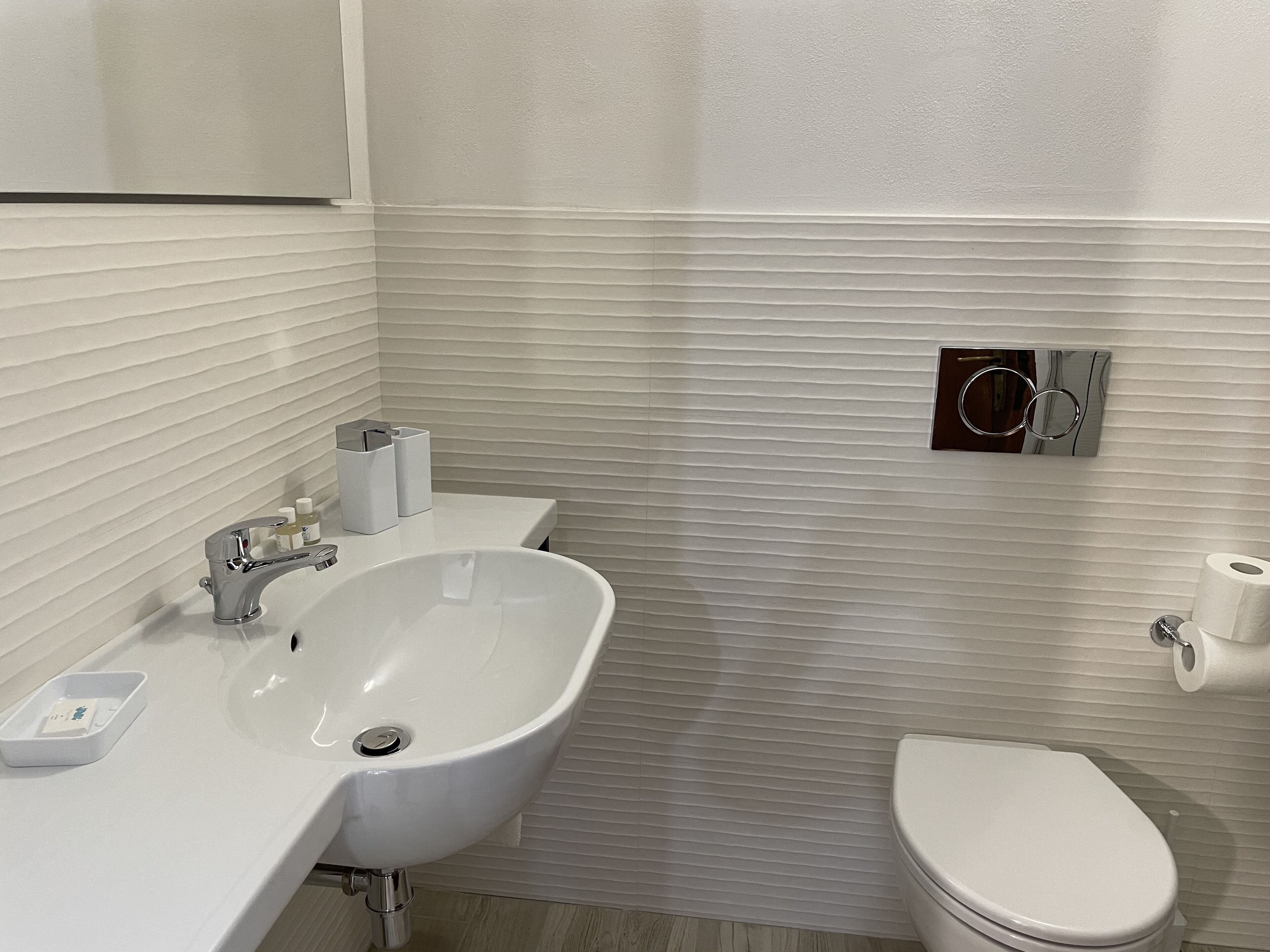 A bathroom with a white sink, mirror, and toilet.