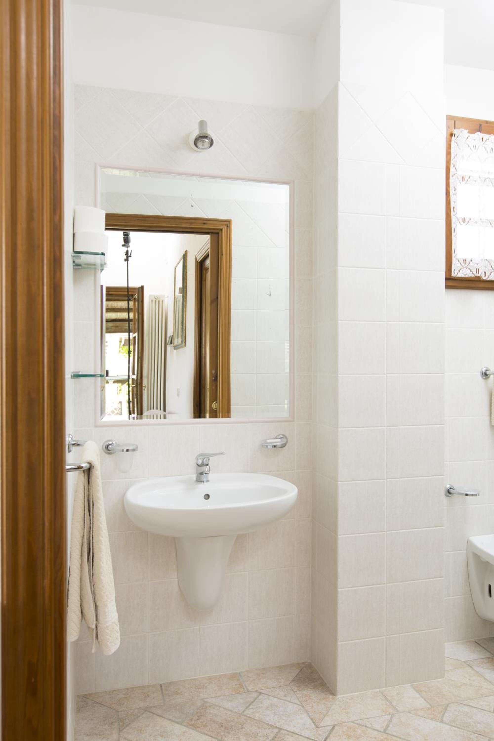 A bathroom with a white sink, a mirror, and a towel rack.