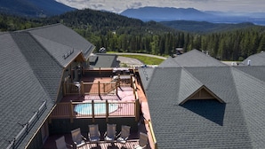 A rooftop with a swimming pool, wooden deck, and a view of a forested valley. - Incredible ski and summer condo!! Direct ski in and out, hot tub , gym, covered parking!! (Whitefish)