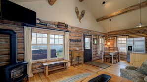 A log cabin interior with a fireplace, wooden furniture, and a view of the outdoors. - Ski-in/ski-out "Alpine Escape" Cowboy Heaven Cabin-360 Degree Mtn View - Hot Tub (Big Sky)