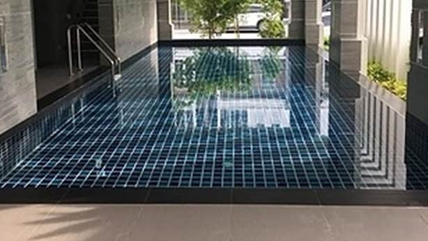A modern indoor swimming pool with a tiled floor and a view of a building outside. - Splash (Bangkok)