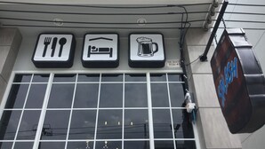 A building with three signs above the windows: a fork and knife symbol, a bed symbol, and a beer mug symbol. - Splash (Bangkok)
