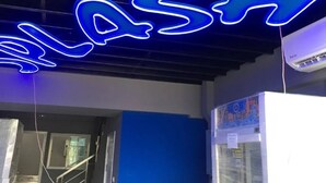 A neon sign spelling "FLASH" in blue, a staircase, and a white air conditioning unit. - Splash (Bangkok)