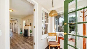 Un couloir doté d’un plancher en bois, d’une cheminée et d’une porte verte avec une fenêtre.