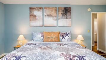 A bedroom with a bed, two nightstands, and three wall art pieces.