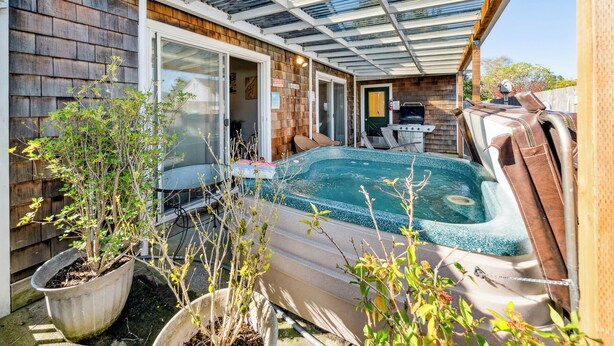 Un jardin avec un jacuzzi, un barbecue et un espace patio couvert.