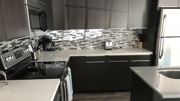 A modern kitchen with a stainless steel refrigerator, a built-in oven, and a microwave.