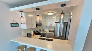 A modern kitchen with white cabinets, stainless steel appliances, and pendant lighting. - #1 Luxury 4BR Rooftop Penthouse @ Jobos Beach (Isabela)