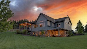 A modern two-story house with a stone foundation, large windows, and a covered porch.