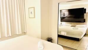 A hotel room with a large bed, a television on the wall, and a mirror reflecting the room. - STRIP 2BR Condo NEARLVCC pet-Friendly Free-wifi on SALE Vegas music festival (Las Vegas)