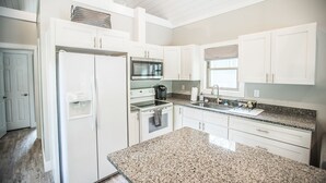 A modern kitchen with white cabinetry, granite countertops, a built-in oven, and a refrigerator. - Coop's Coop: A newly renovated studio cottage (Hendersonville)