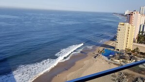 Una playa con piscina y un edificio al fondo.