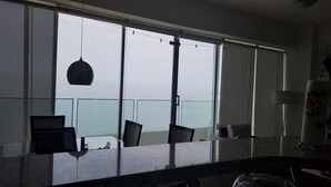 Una habitación con ventanas amplias, una lámpara colgante y vista al mar.