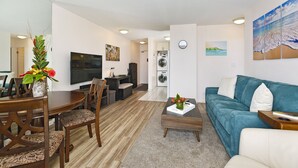 A modern living room with a dining area, a TV, a sofa, and a coffee table. - Great for Families! Partial Ocean/Canal/Diamond Head Views! Pool/WiFi/Parking (Honolulu)