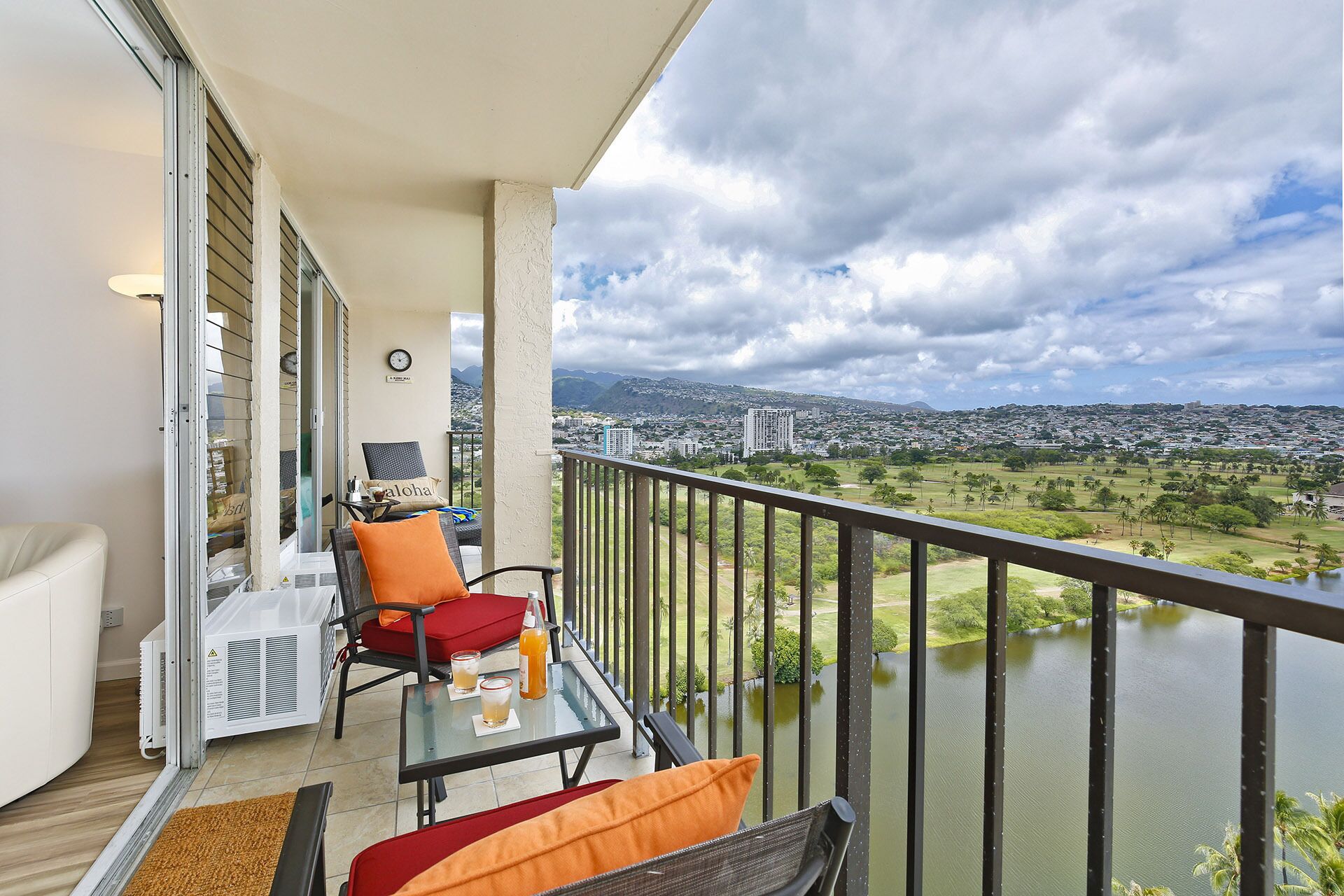 A balcony with a table, chairs, and a view of a river and cityscape.
