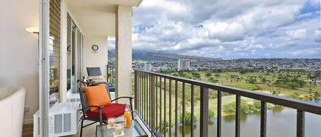 A balcony with a table, chairs, and a view of a river and cityscape.
