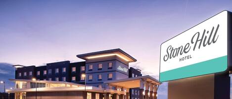 Hotel Stone Hill con diseño moderno, que presenta un cartel llamativo y una fachada bien iluminada.