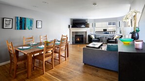 A modern living room with a fireplace, dining area, and seating. - Super Location, Free Parking, 3 Bedroom + Loft, 3.5 Ba, Sleeps 10, Tesla Charger (Seattle)