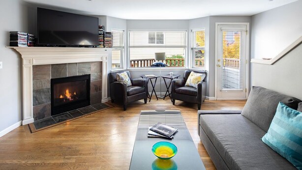 A living room with a fireplace, a television, and a sofa. - Super Location, Free Parking, 3 Bedroom + Loft, 3.5 Ba, Sleeps 10, Tesla Charger (Seattle)