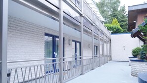 A building with a white brick facade, multiple doors, and a metal railing along the exterior. - Hotel B8 Voerde (Voerde)