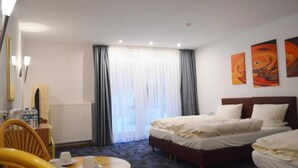 A hotel room with a bed, a chair, a table with cups, a radiator, and curtains. - Hotel B8 Voerde (Voerde)