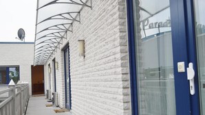 A building with a white brick facade, a blue door, and a satellite dish. - Hotel B8 Voerde (Voerde)