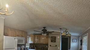 A kitchen with wooden cabinets, a white refrigerator, a stove, and a ceiling fan. - Ranch House (Thompson Springs)