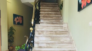 A staircase with a handrail, a potted plant, and a wall-mounted painting.