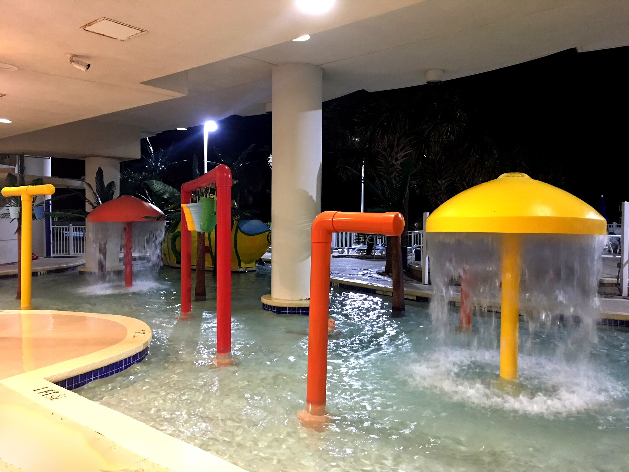 An indoor water play area with multiple water features and a pool.