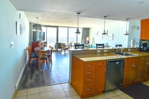 A spacious kitchen with wooden cabinets, a dishwasher, and a large island with a sink.