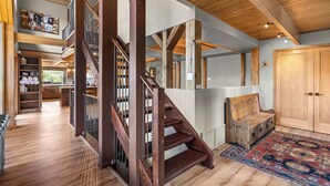 A spacious interior with a wooden staircase, a cozy seating area, and a kitchen visible in the background.