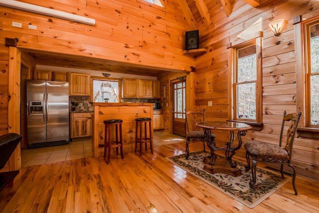 L’intérieur d’un chalet en bois comprend une cuisine, un coin repas et une grande fenêtre.