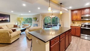 A spacious living area with a large island, wooden cabinets, and a modern kitchen with stainless steel appliances. - Powderhorn C202 2 Bedroom Condo by RedAwning (Breckenridge)