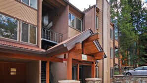A multi-story building with a wooden exterior, a covered outdoor area with stone pillars, and a staircase leading to an upper level.