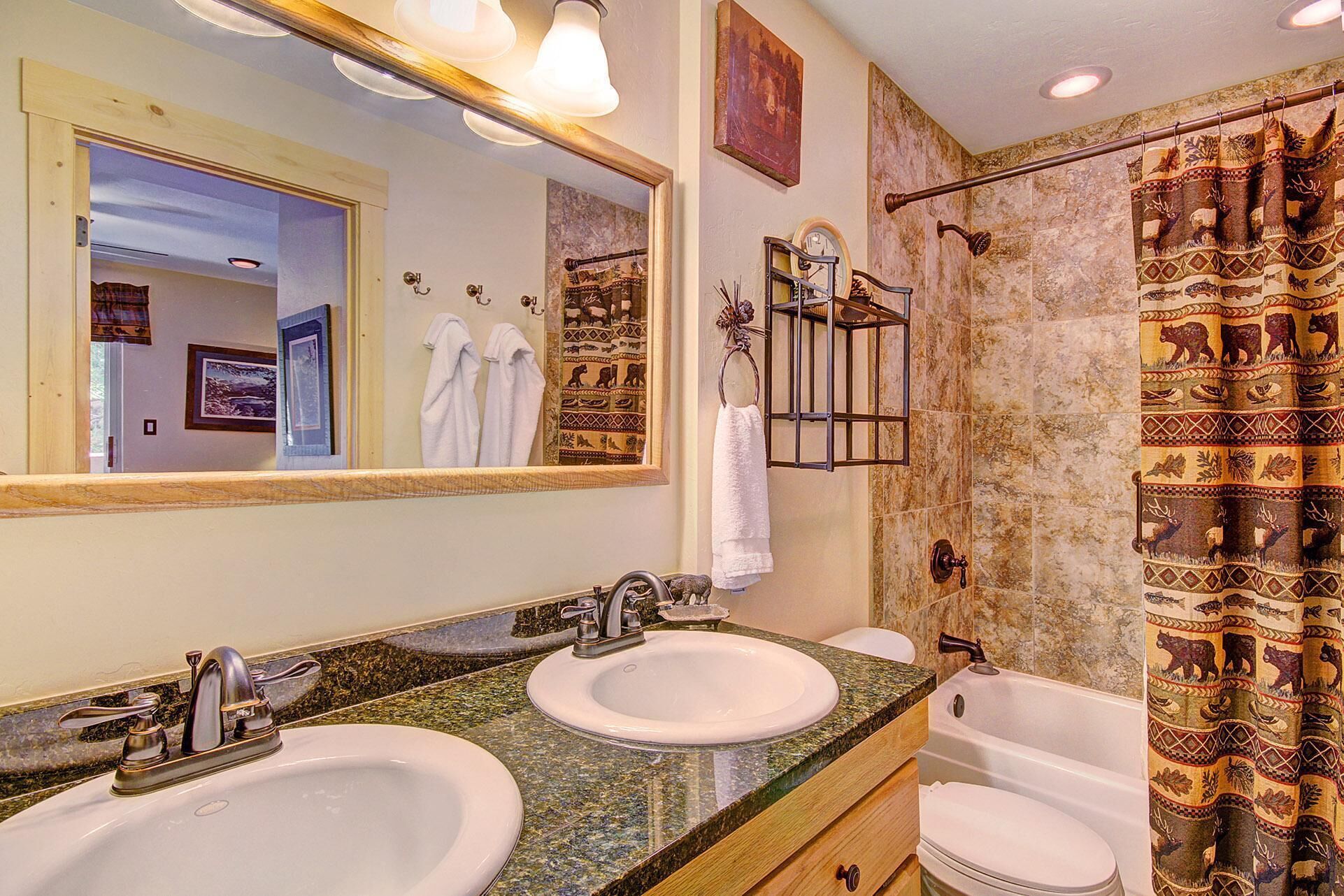A bathroom with two sinks, a bathtub, a shower with a curtain, and a mirror with lights.