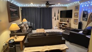 A living room with a sofa, two side tables, a coffee table, a TV, and a ceiling fan.