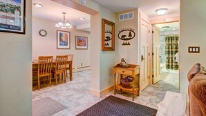 A hallway with a dining area, a welcome sign, and a bathroom visible through an open door.