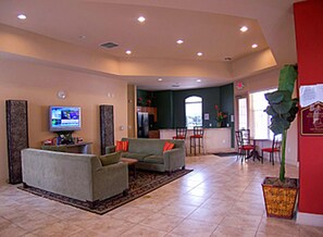 A spacious living area with a large sofa, a television, and a dining area with chairs and a table. - Kinsale (Davenport)